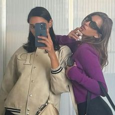 A woman wearing a purple sweater, black skirt, and black bag