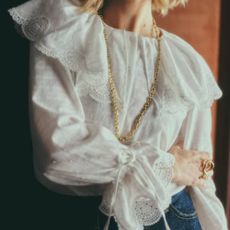 A female model wearing a feminine, frilly blouse from Sezane.