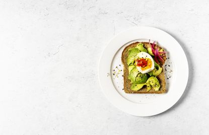 A plate with a fancy avocado toast and egg. 