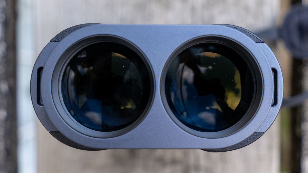 A close-up of the lenses on the Fujifilm Techno-Stabi TS-L 1640 image-stabilized binoculars with wooden planks in the background.
