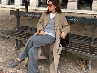 Fashion influencer @deborabrosa sitting on a park bench in Paris wearing the controversial leather boat shoe trend.