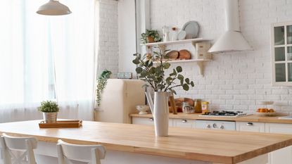 Maximize space in a small kitchen like this one with wooden a dining table white walls and open shelving