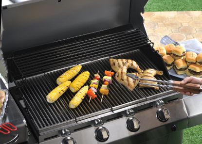 A close up of a gas grill grate cooking food