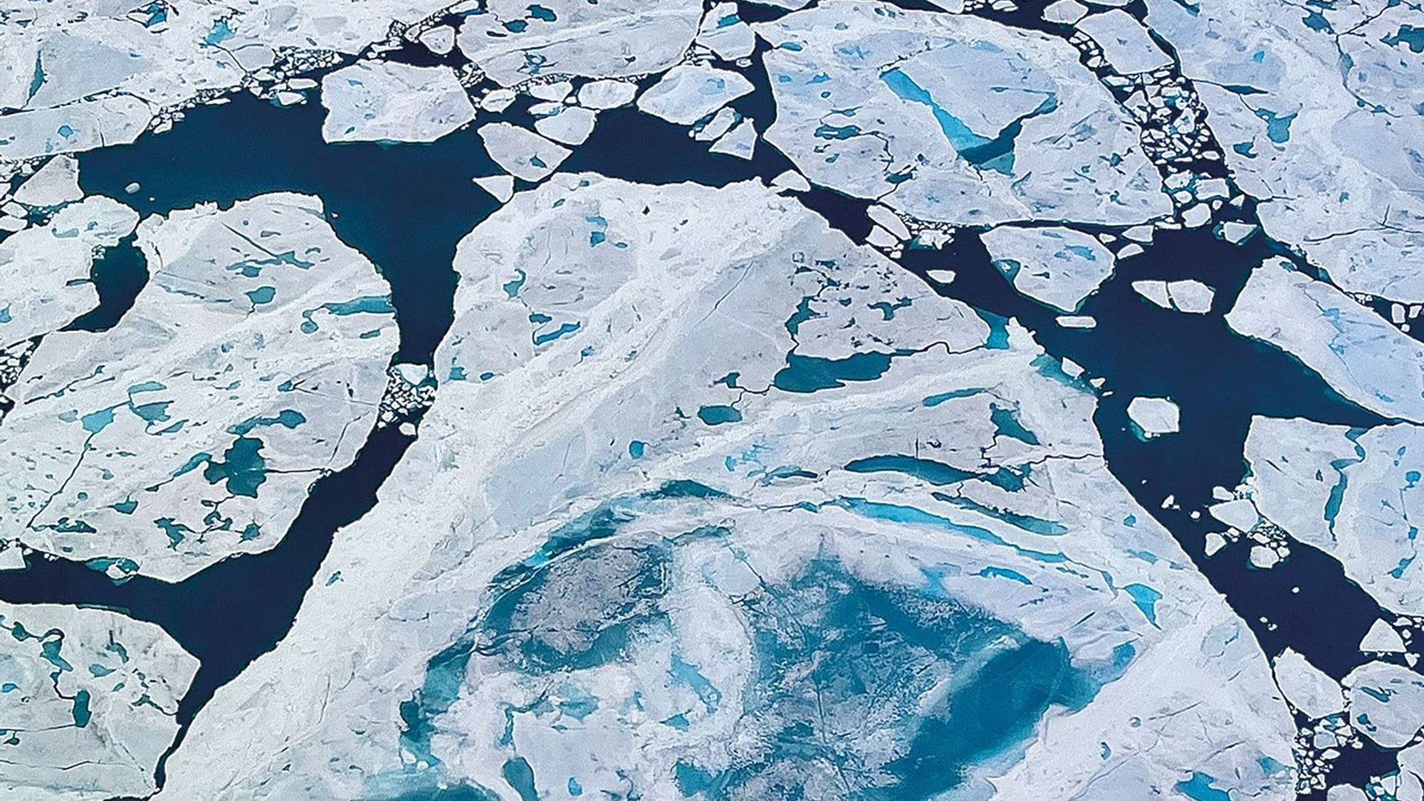 An image showing arctic ice that's white and blue broken up over the ocean.