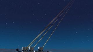 A series of small round buildings at the bottom left of the image with four yellow lasers pointing into the top right of the image over a dark blue night sky.