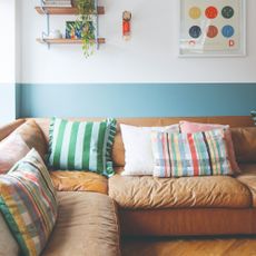 A living room with two-tone walls in white and sky blue and a brown leather corner sofa