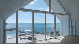 Floor to ceiling windows overlooking a terrace above the sea