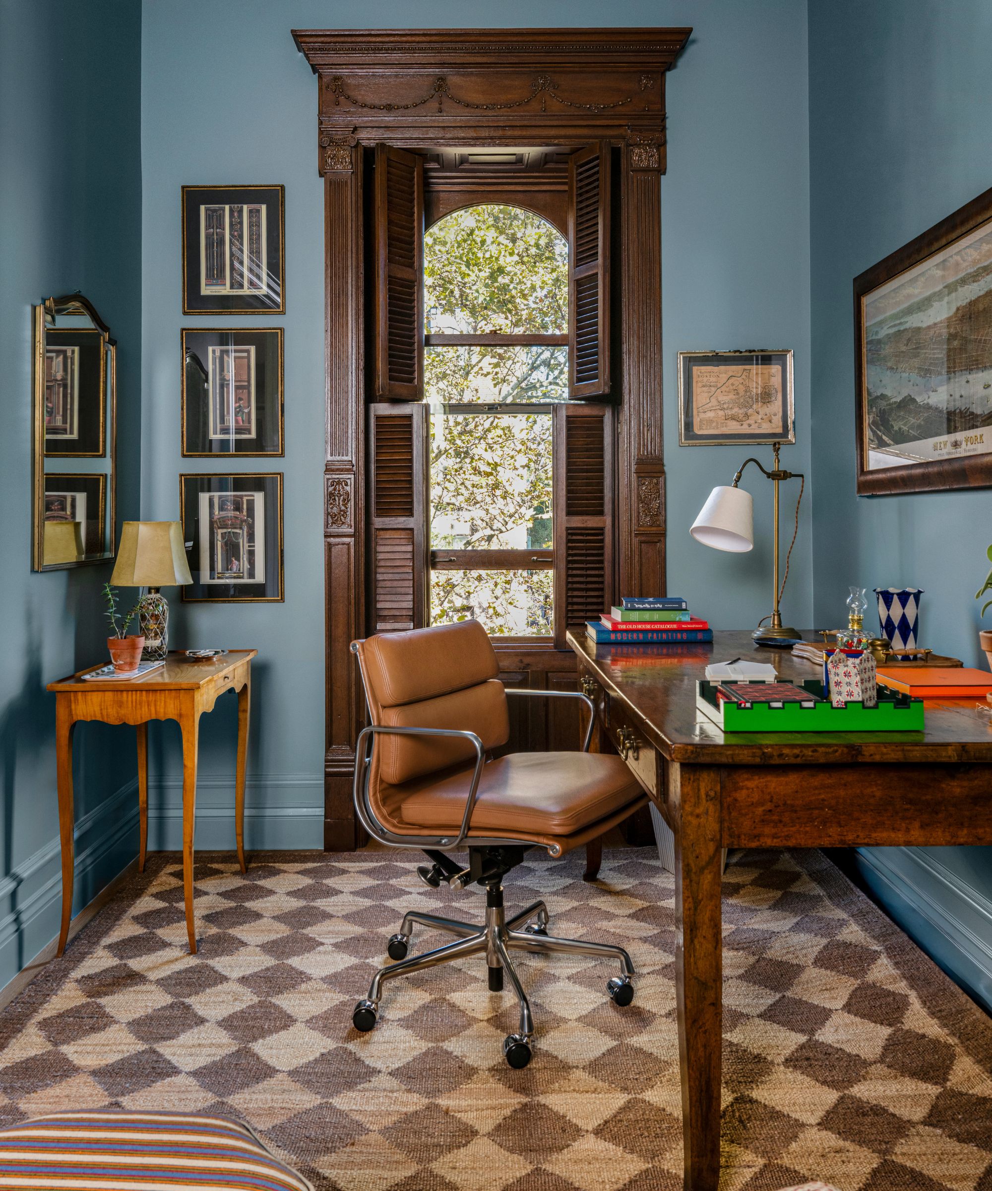 a blue gentleman's home office with mahogany brownstone windows and an antique desk
