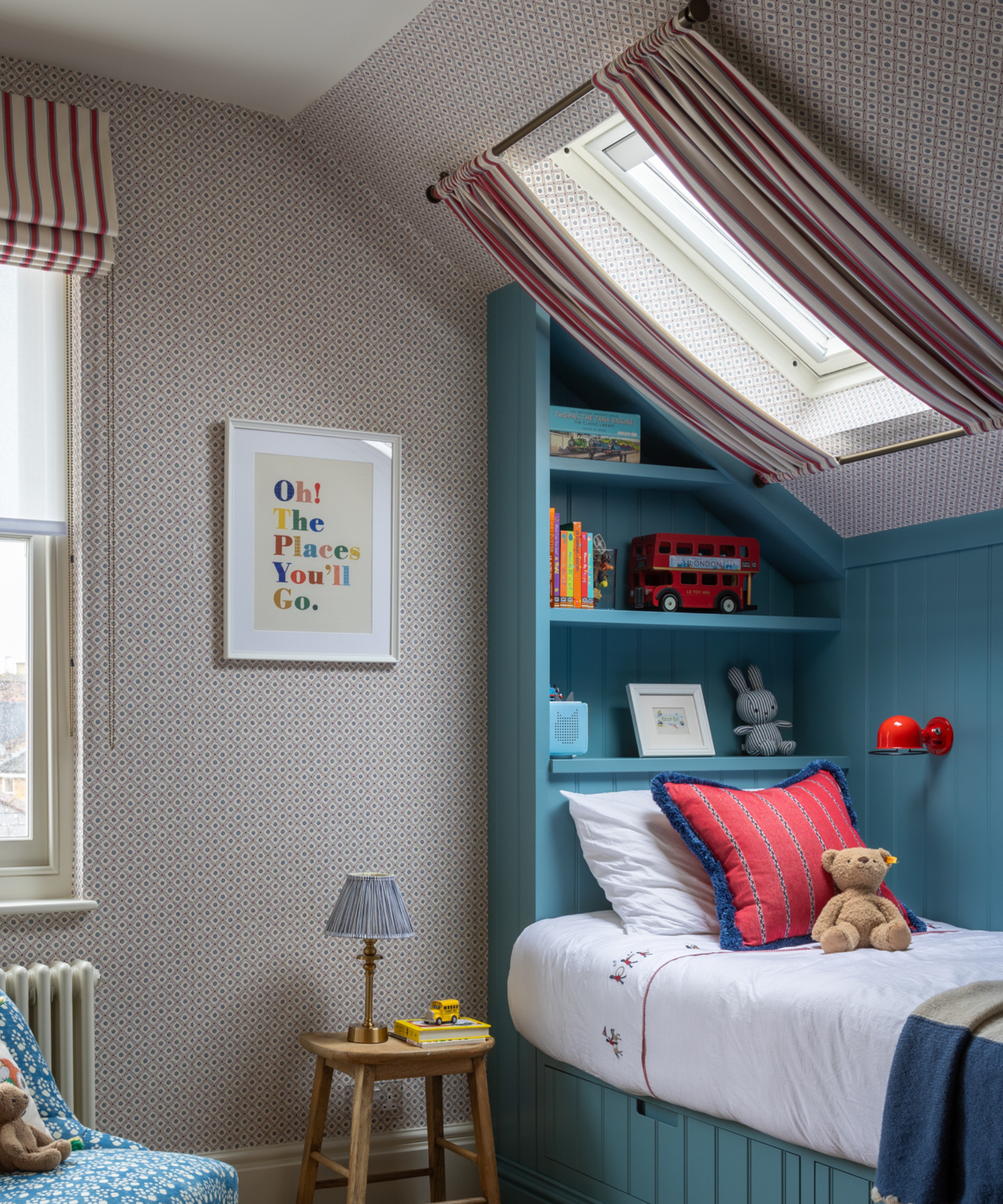 a child&#039;s bedroom with a built-in bed, red patterned wallpaper, and striped curtains hanging in front of the skylight