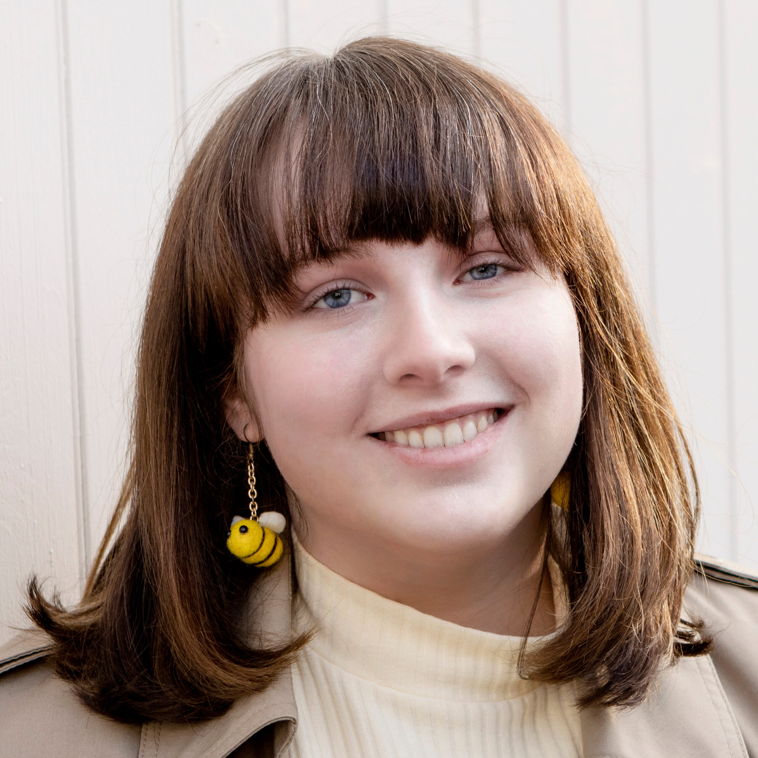A headshot of a woman with dark brown hair and a fringe smiling at the camera