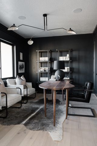 black office with white ceiling and pale wood floors, dark wood table and black and white chairs