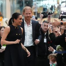 Meghan Markle and Prince Harry greeting a crowd of people taking their photos