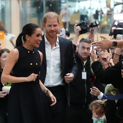 Meghan Markle and Prince Harry greeting a crowd of people taking their photos