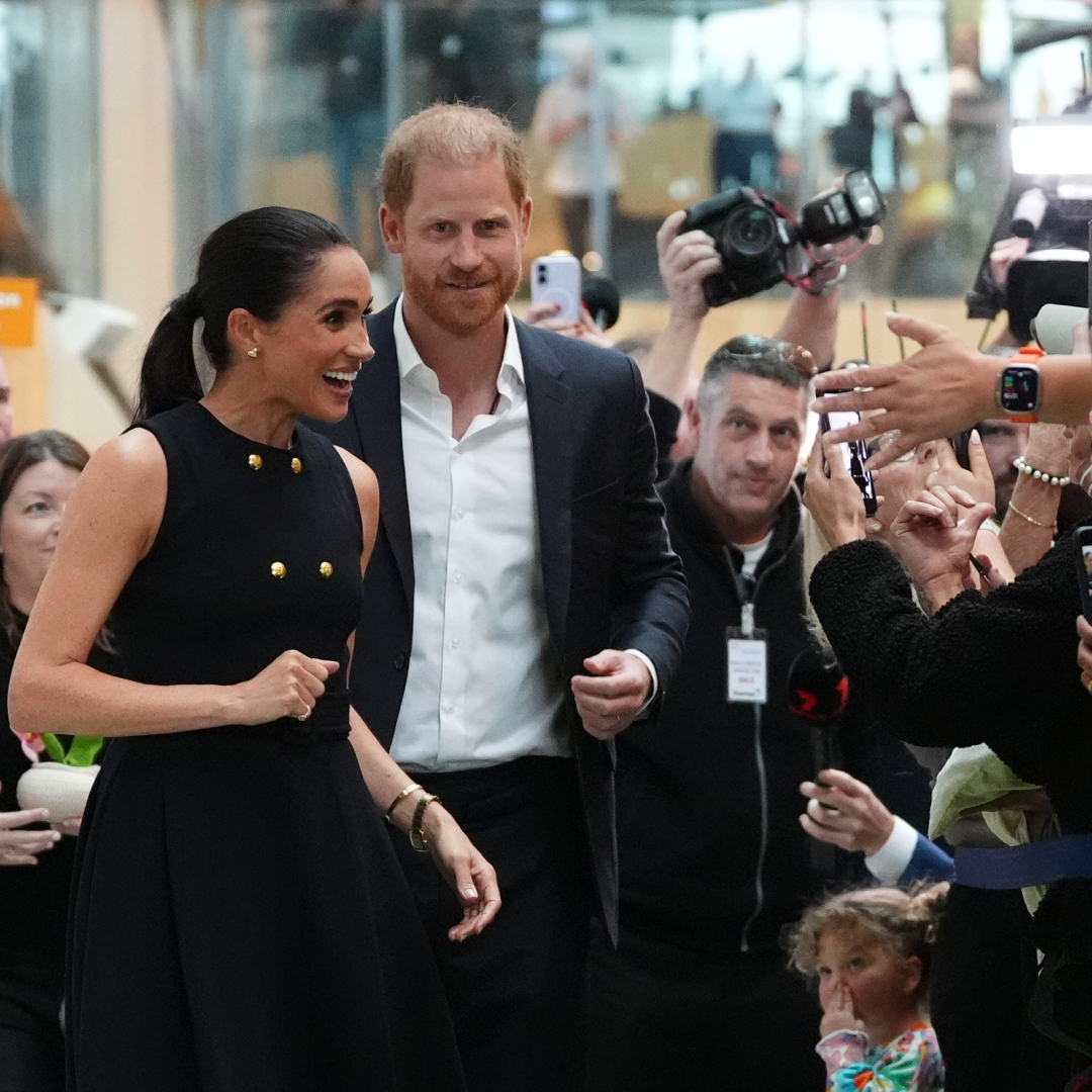 Meghan Markle and Prince Harry greeting a crowd of people taking their photos 
