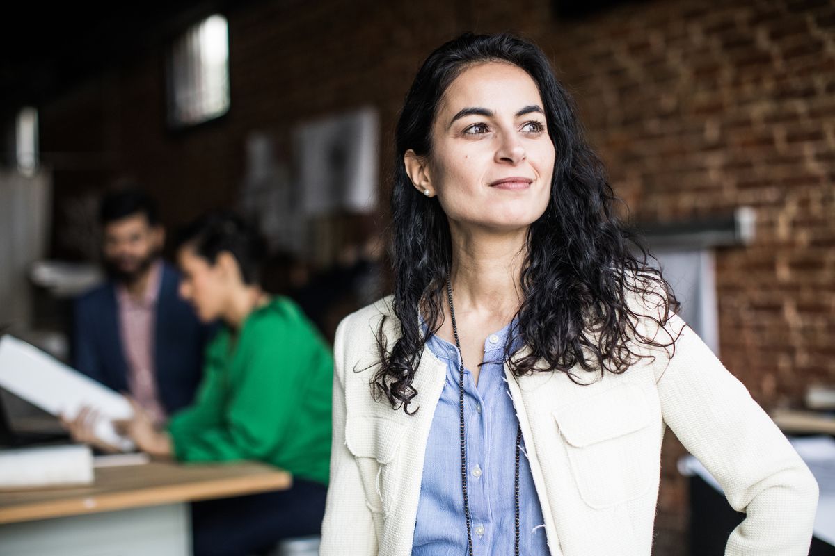 A business woman stood in a bare-brick modern office