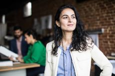 A business woman stood in a bare-brick modern office