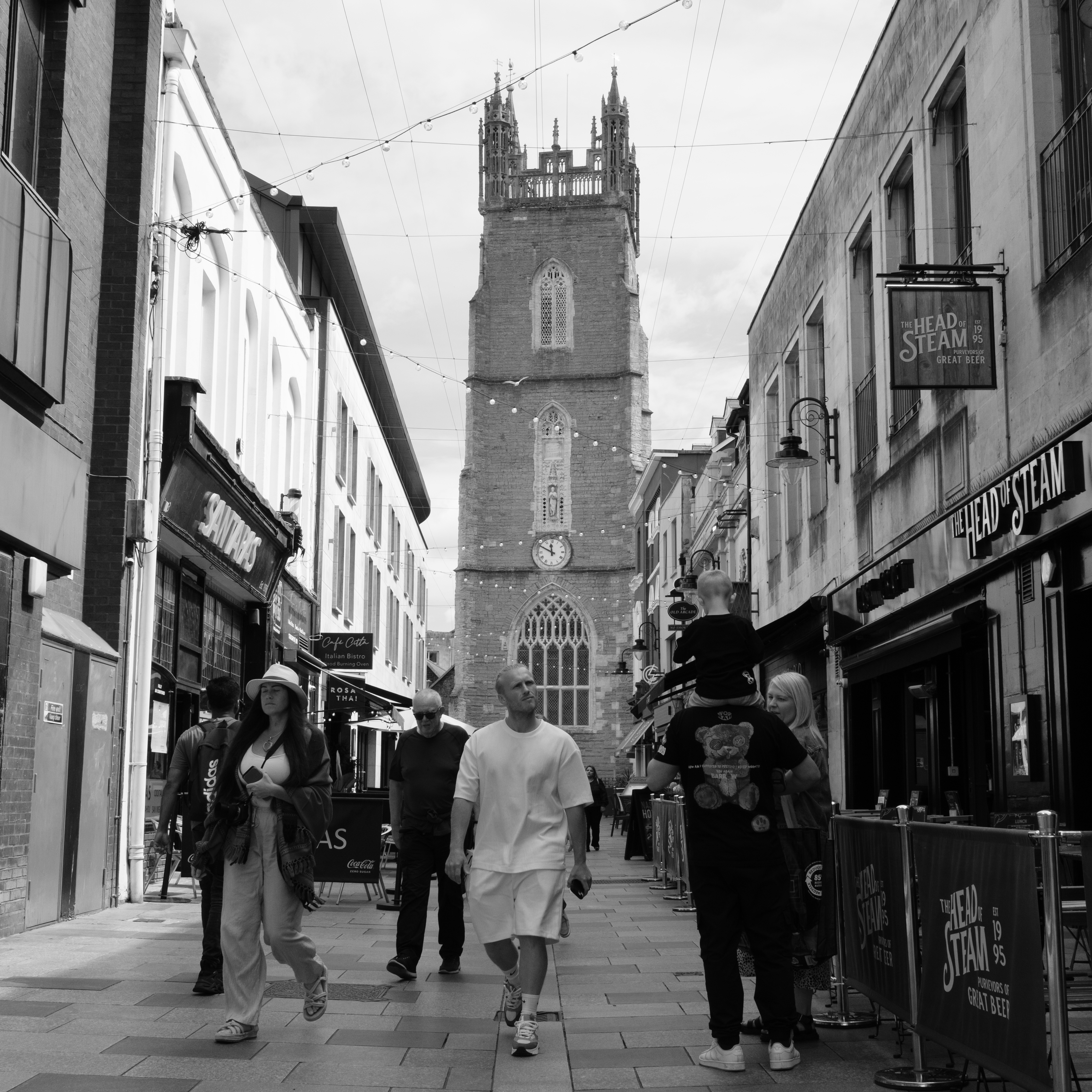 A street scene showing a couple walking down a street with a church in the background, taken on the Fujifilm X-E5.