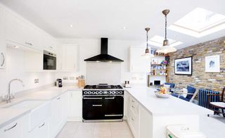 open plan kitchen diner extension with white units and exposed brick wall