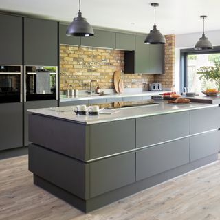 Grey kitchen with large island, pendant lighting and exposed brick wall