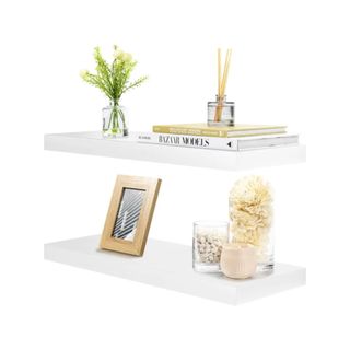 Two white floating shelves with decorations on it
