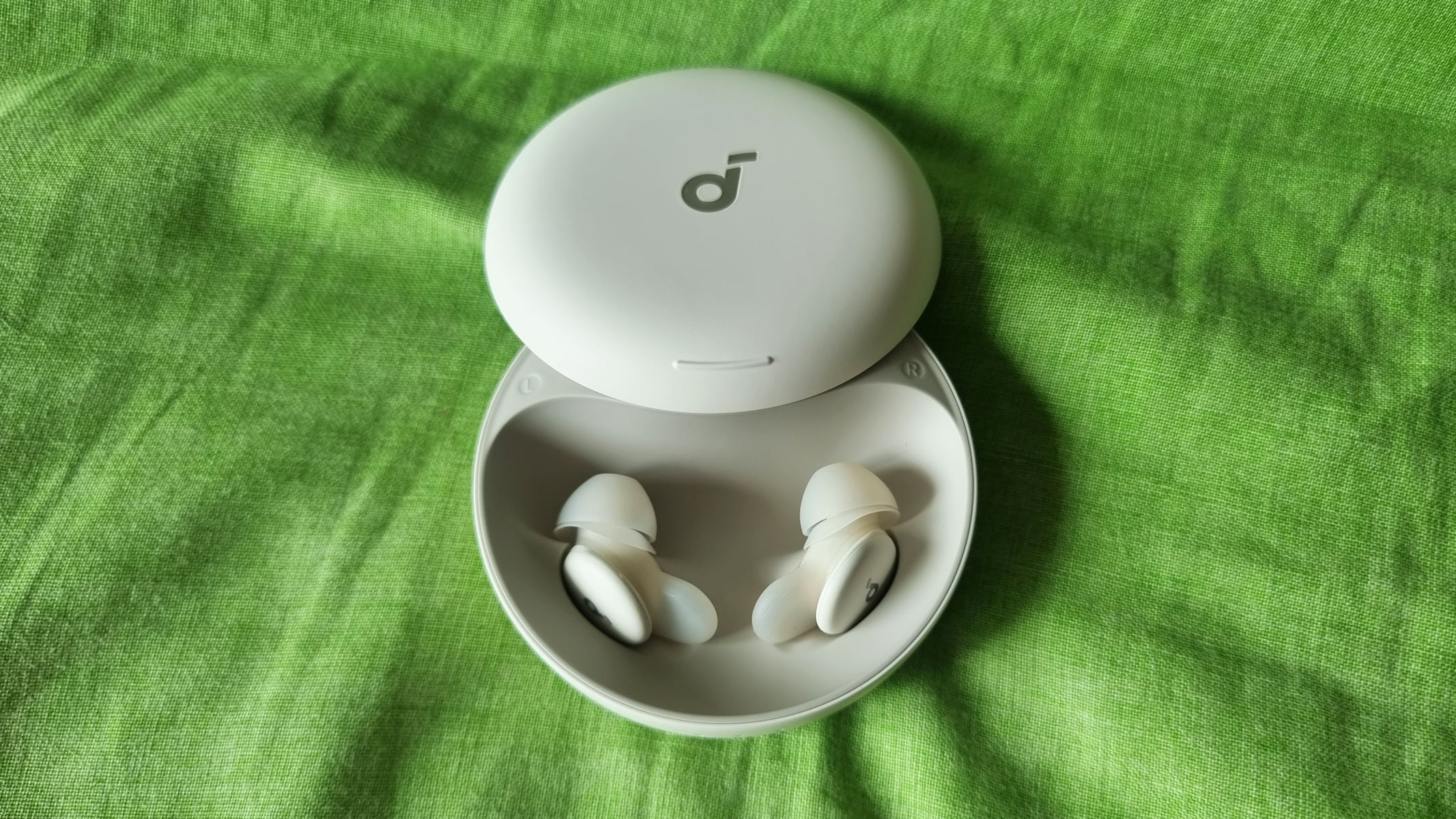 Soundcore Sleep A30 in an open case on a green pillow