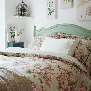 bedroom with bed having floral printed bedsheet and photoframe on wall