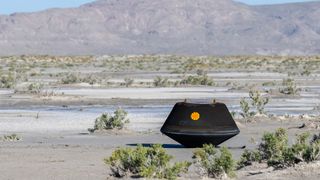 A black hexagonal box with an orange eye in the center, sitting in the Utah desert. This is the OSIRIS-REx return capsule, safely landed on Earth