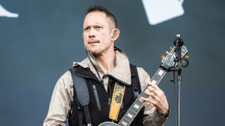 Matt Heafy on stage looking serious with a guitar