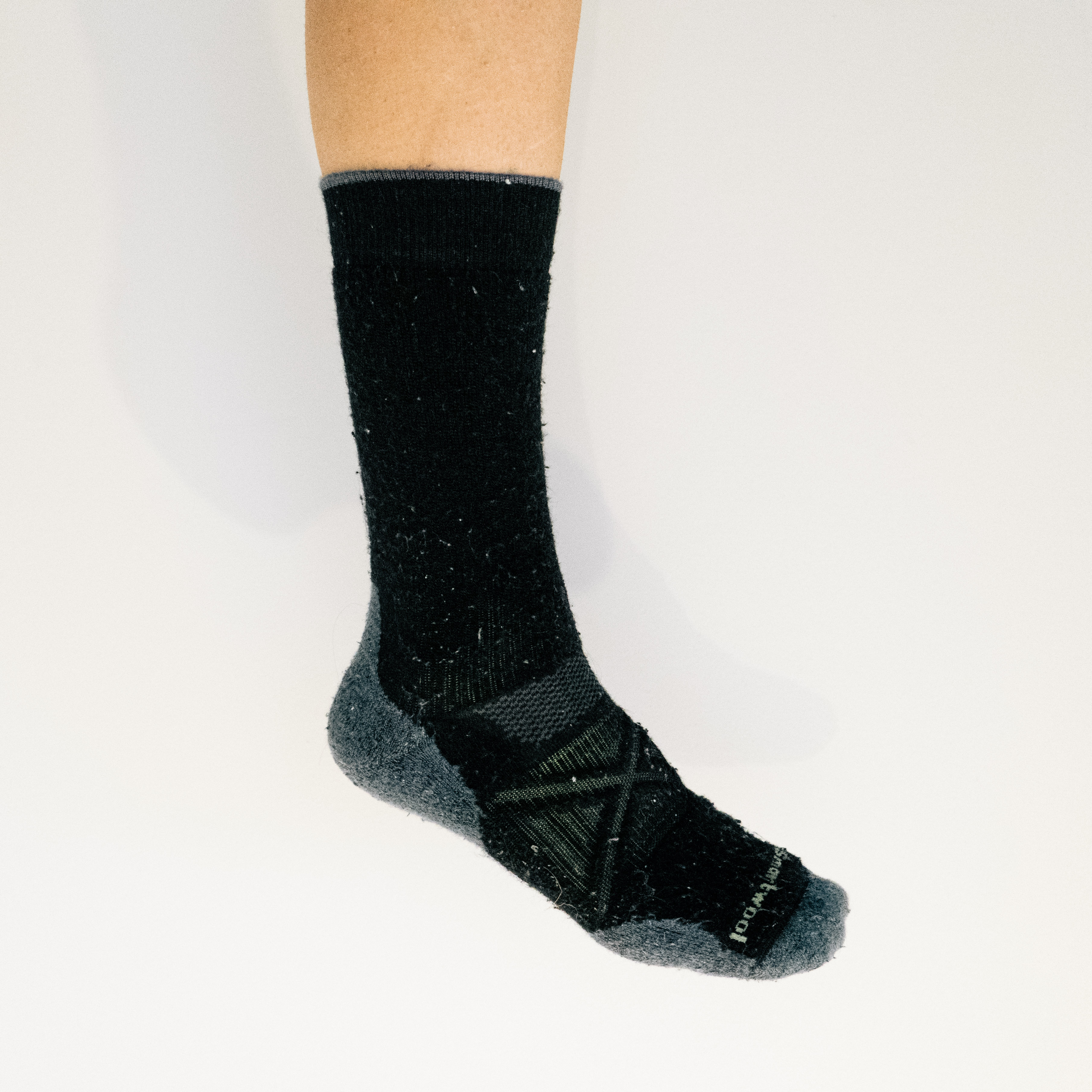 A white leg wears a black cycling sock against a white background