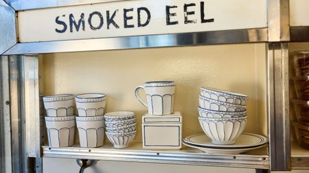 Russ & Daughters x West Elm white ceramic serveware lined in blue pictured atop a mid-century style shelf framed in chrome