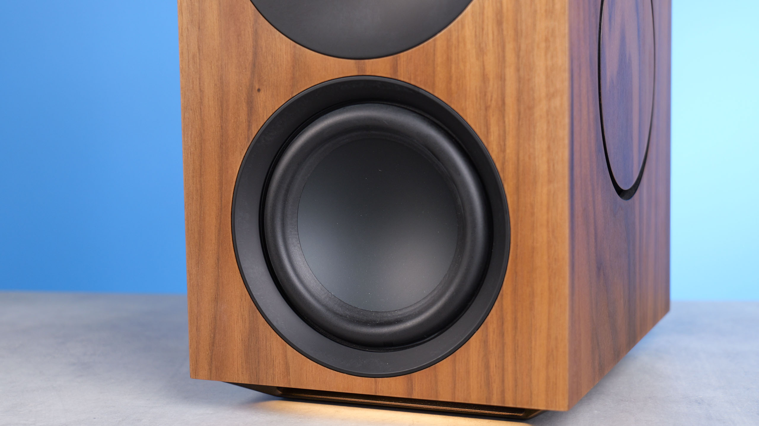 The Cambridge Audio L/R X main woofer, positioned on a stone surface with a blue background
