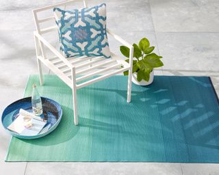 ombre effect outdoor rug and white chair on a patio