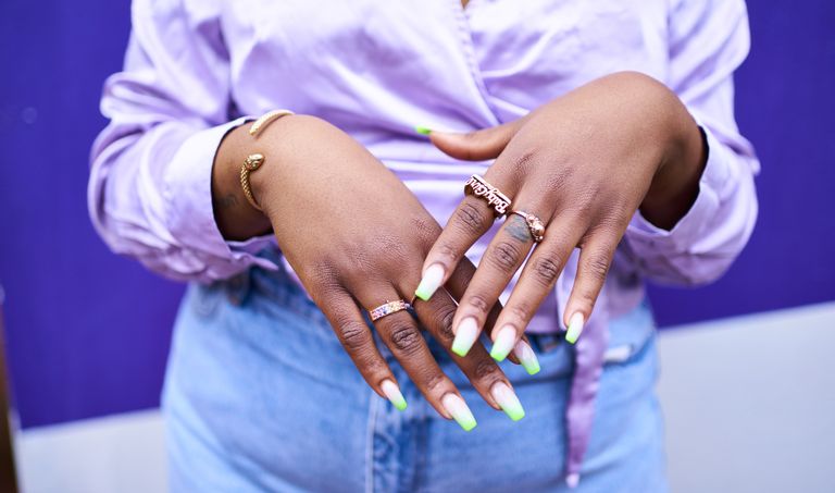 Close up of woman's hands with lots of gold rings and painted nails
