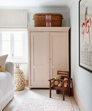 children's bedroom with pale pink armoire and patterned rug