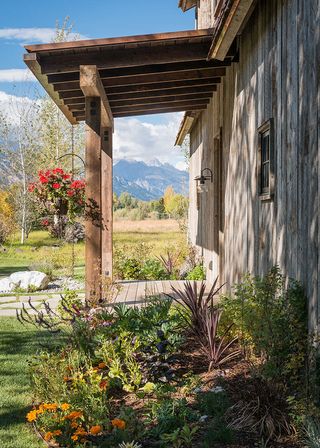 Hanging planters on a rustic wooden porch with a mountainous backdrop.