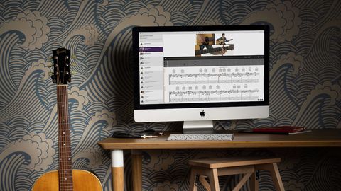 TrueFire website running on a computer with an acoustic guitar off to the left