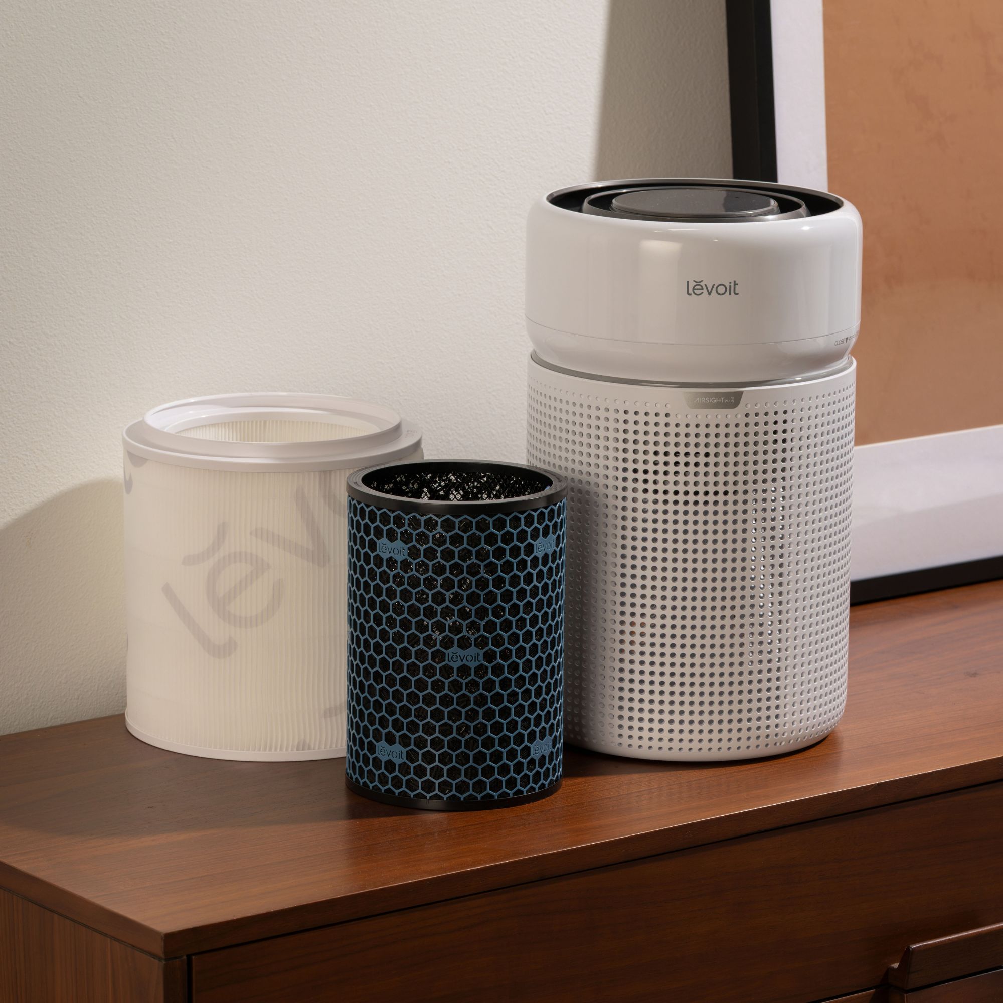 Levoit Eleva 300X Smart Air Purifier and its separate filters sitting on a wooden side table