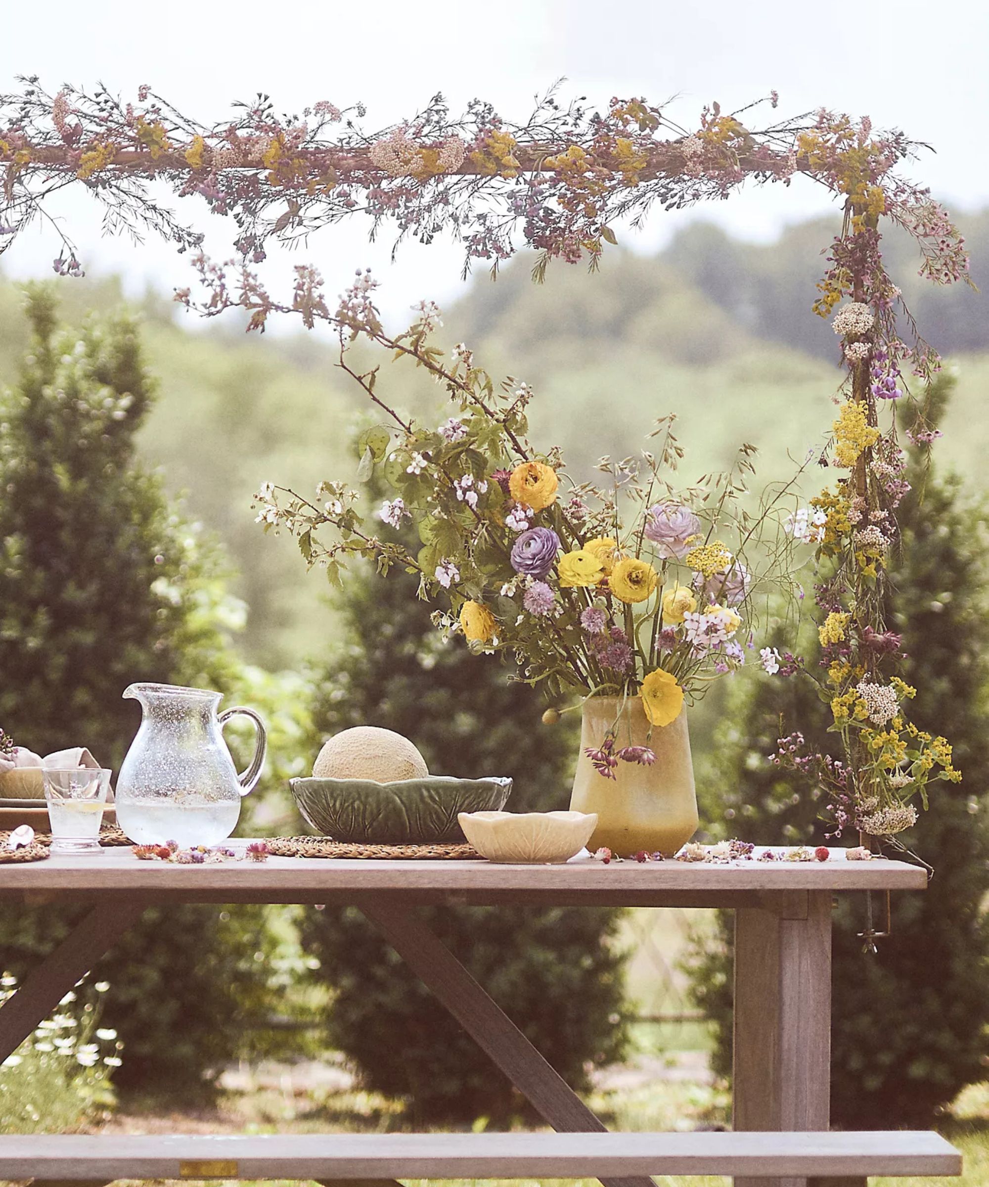 Outdoor table with overhead floral table rod and vases of flowers on the table