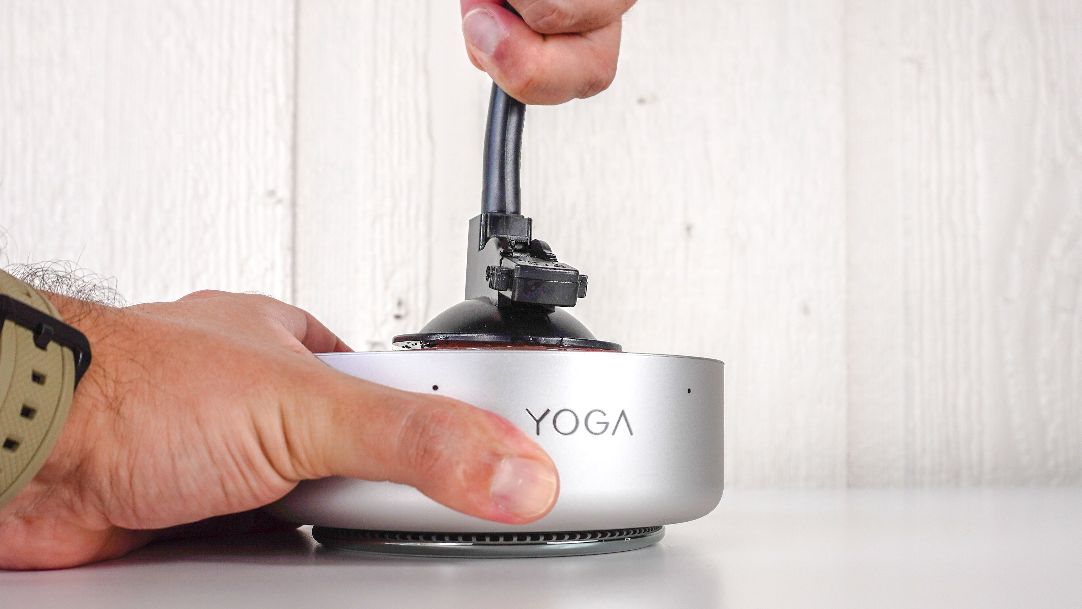 A person using a suction cup to remove the top lid of the Lenovo Yoga Mini mini PC