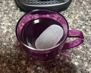 A cup of coffee in purple mug with an ice cube dropped in
