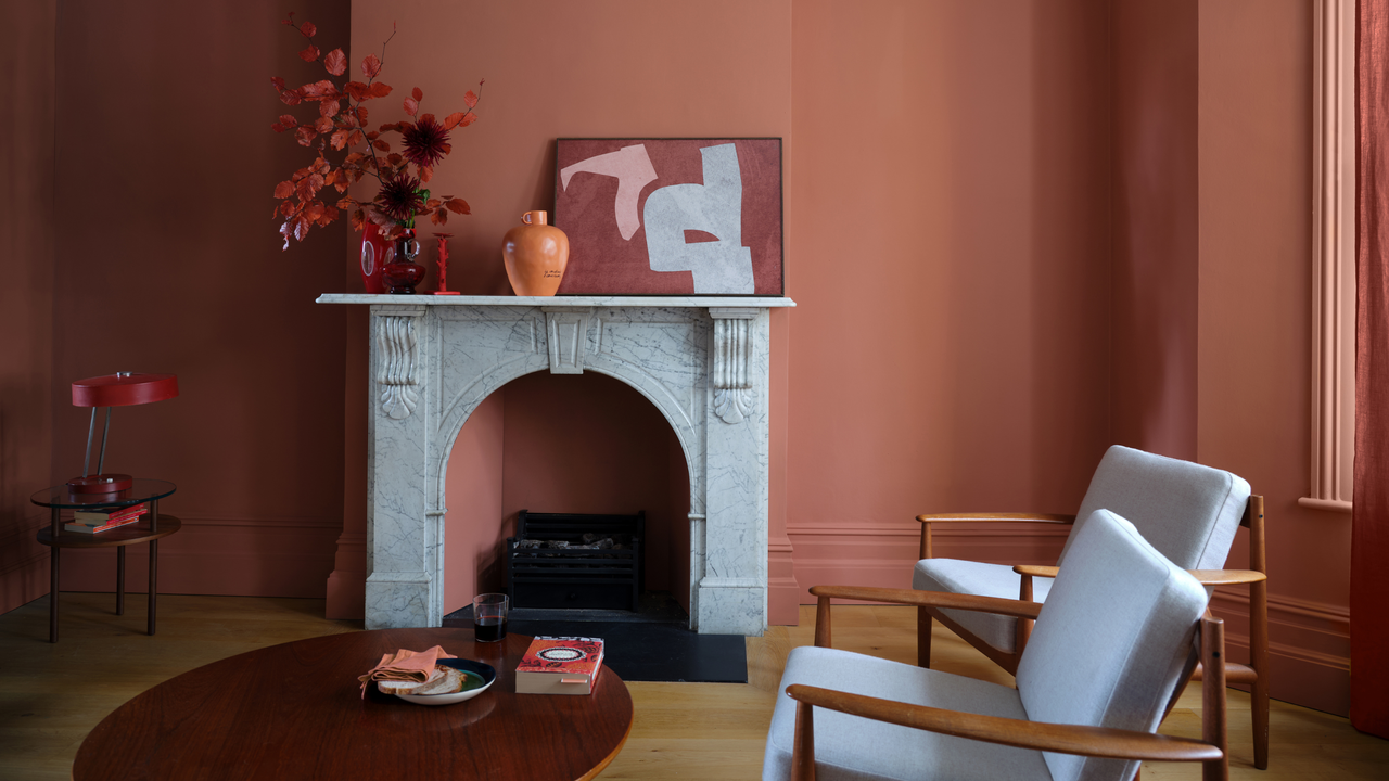 a red painted living room with marble fireplace and two armchairs 