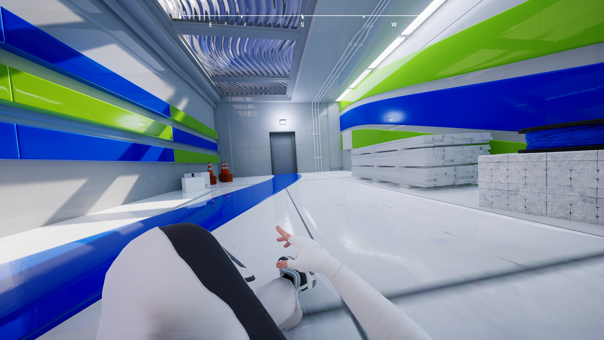 A parkour runner in first person perspective slides down a sleek hallway.