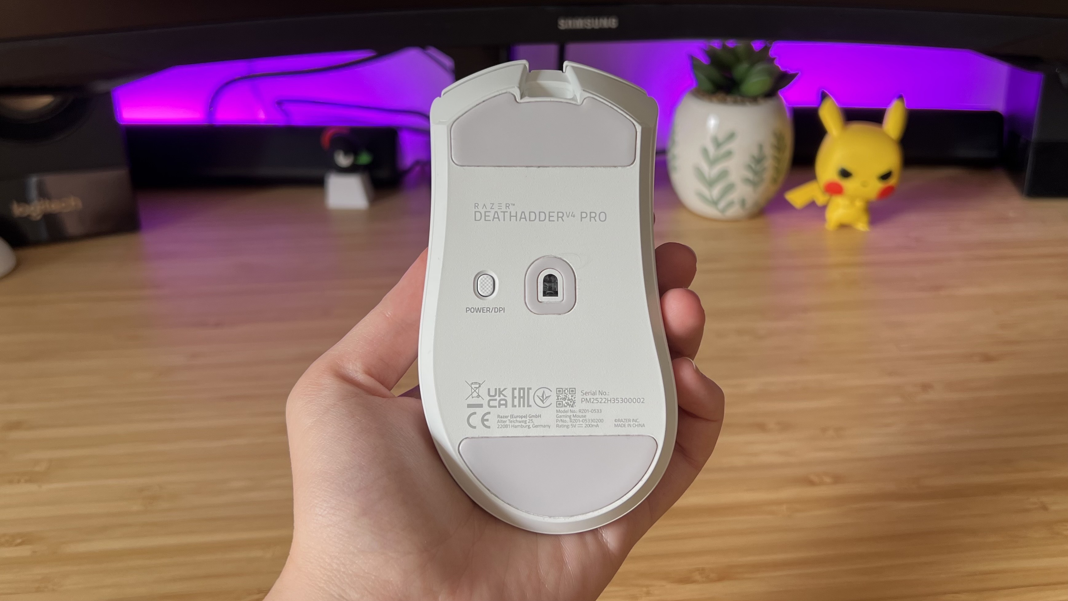Hand holding Razer DeathAdder V4 Pro gaming mouse with underside showing sensor