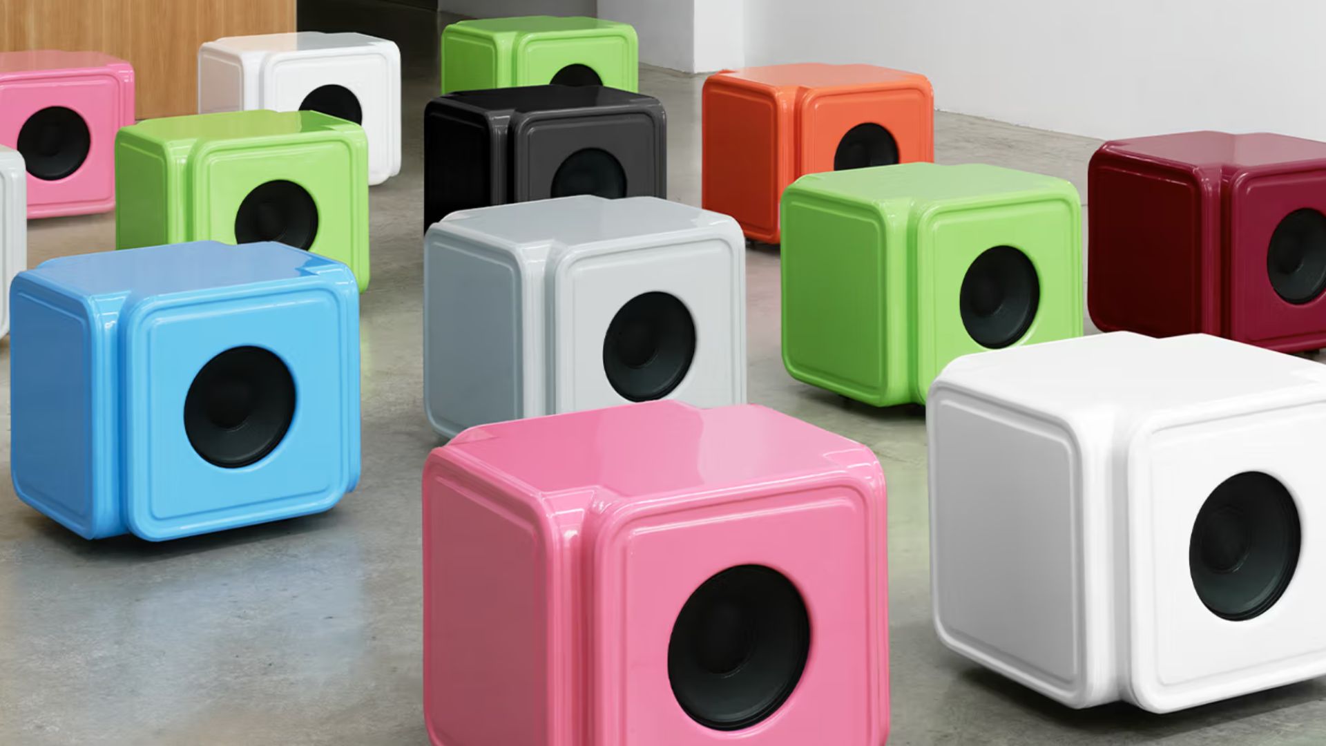 an image of twelve of the CALIPER Alaska Alaska speakers in their full range of colours. The speakers are lined up on the floor of a stuido