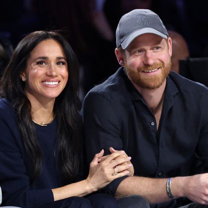 Prince Harry and Meghan Markle sitting next to each other in black outfits