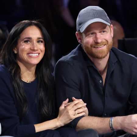 Prince Harry and Meghan Markle sitting next to each other in black outfits