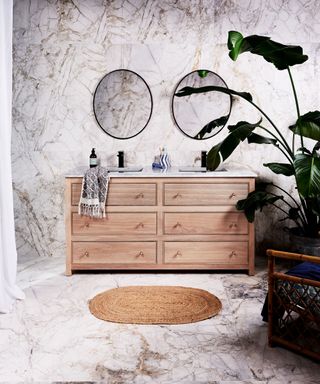 A marble tile drenched bathroom with wood furniture