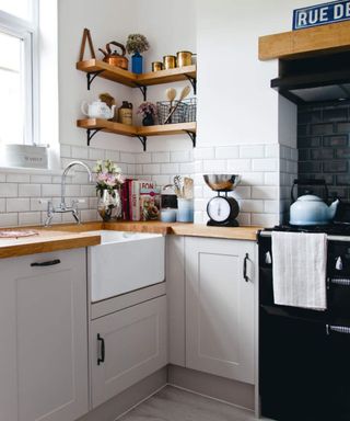 hite and pale grey fitted kitchen, wood worktops, tiled walls, blue tiled splashback, wood shelves, cookbook display