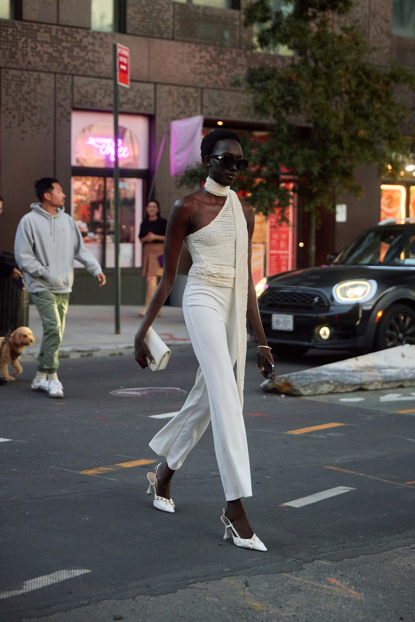 A new york spring 2025 fashion week attendee wears a beige scarf top, white pants, and white heels