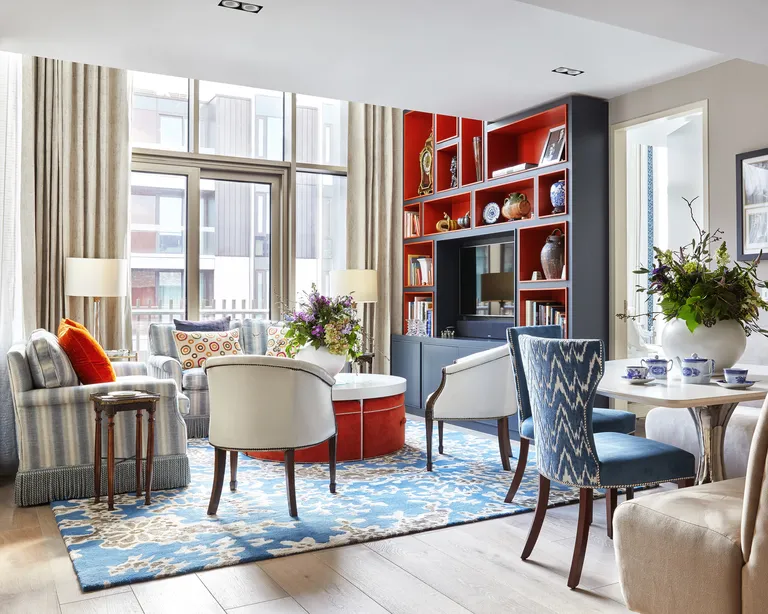 A living room with blue and orange decor, two sofas and table with dining bench